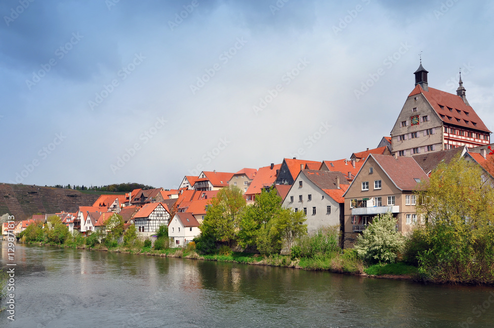 Riverside with historical landmarks, towers, half-timbered houses and trees on the background the stormy sky. Besigheim, Baden-Wurttemberg, Germany.