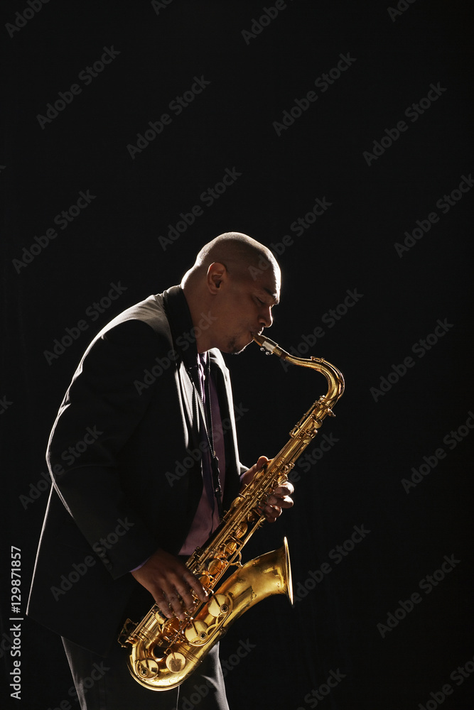 Fototapeta premium Side view of an African American man playing saxophone against white background