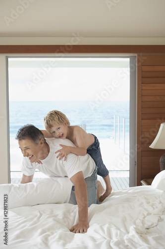 Happy father and son playing together in bed