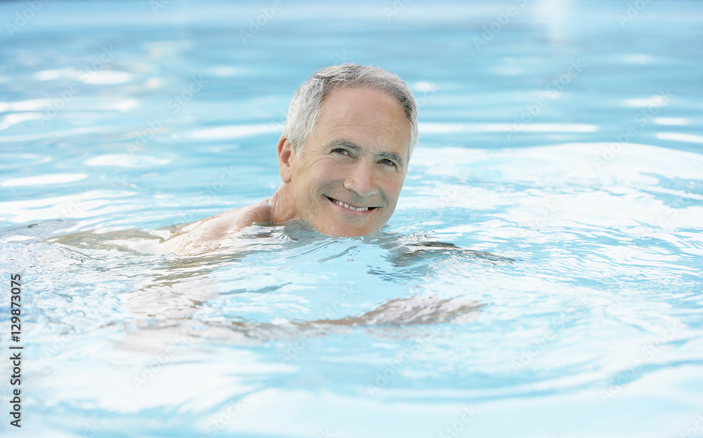 Portrait of happy middle aged man swimming in pool