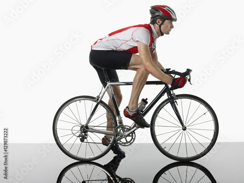 Side view of a bicyclist mounted on bicycle against white background