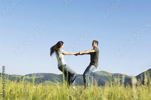 Side view of young loving couple playing against mountain range and clear sky at park
