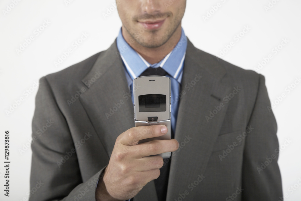 Midsection of a businessman using mobile phone over gray background Midsection of a businessman using mobile phone over gray background
