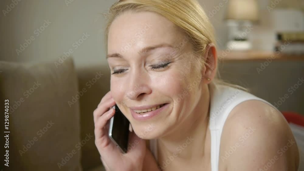 woman talking on the phone while lying on the couch at home woman talking on the phone while lying on the couch at home