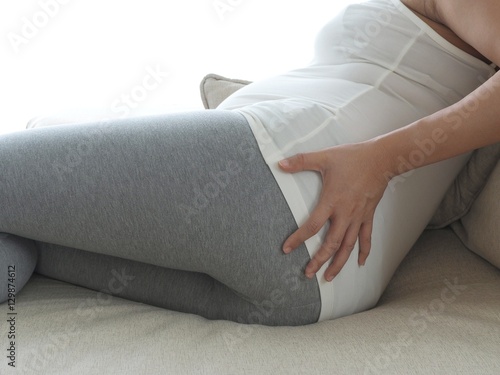 Pregnant woman with painful back on the sofa. Concept of pregnancy healthcare. photo