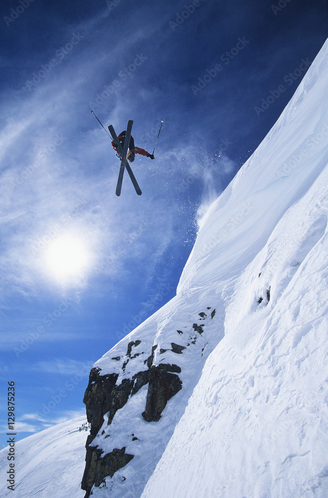 Low angle view of freestyle skier jumping from mountain ledge