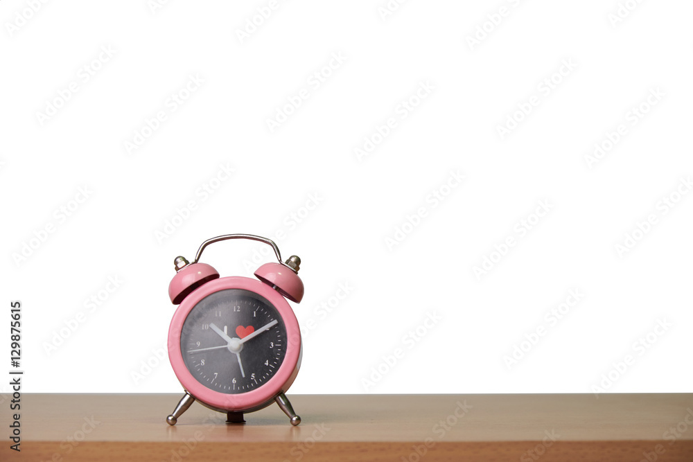 A pink alarm clock on wooden floor and white background. A pink alarm clock on wooden floor and white background.