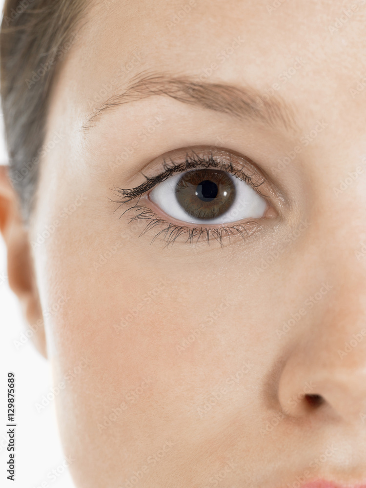Closeup portrait of an eye of a young woman against white background