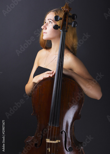  Beautiful girl with a cello in the dark. Violonchello. Girl with long straight hair 