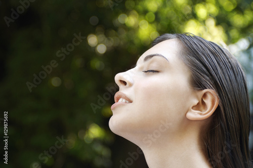 Side view closeup of young woman with eyes closed in park