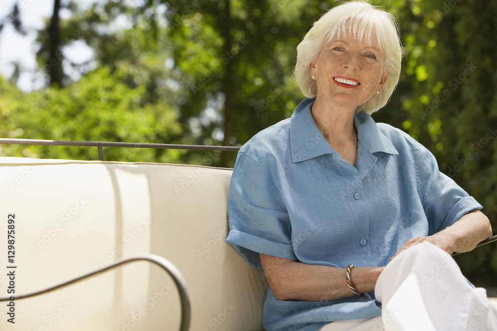 Portrait of beautiful senior woman relaxing on sofa in backyard