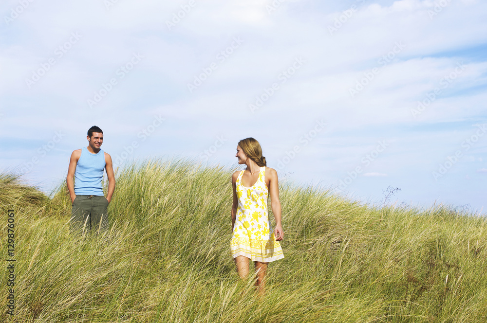 Young romantic couple walking in tall grass at beach Young romantic couple walking in tall grass at beach