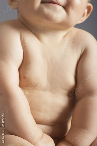 Midsection of baby girl sitting isolated on colored background