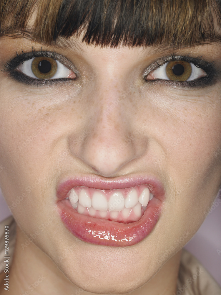 Fototapeta premium Extreme closeup of a beautiful angry young woman clenching teeth