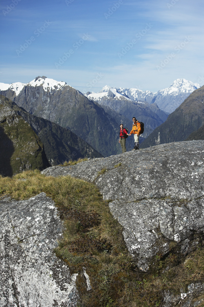 Male and female hikers on rock against mountains