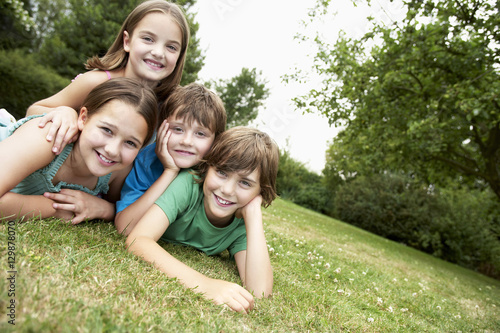 Portrait of two young girls and boys lying in park together