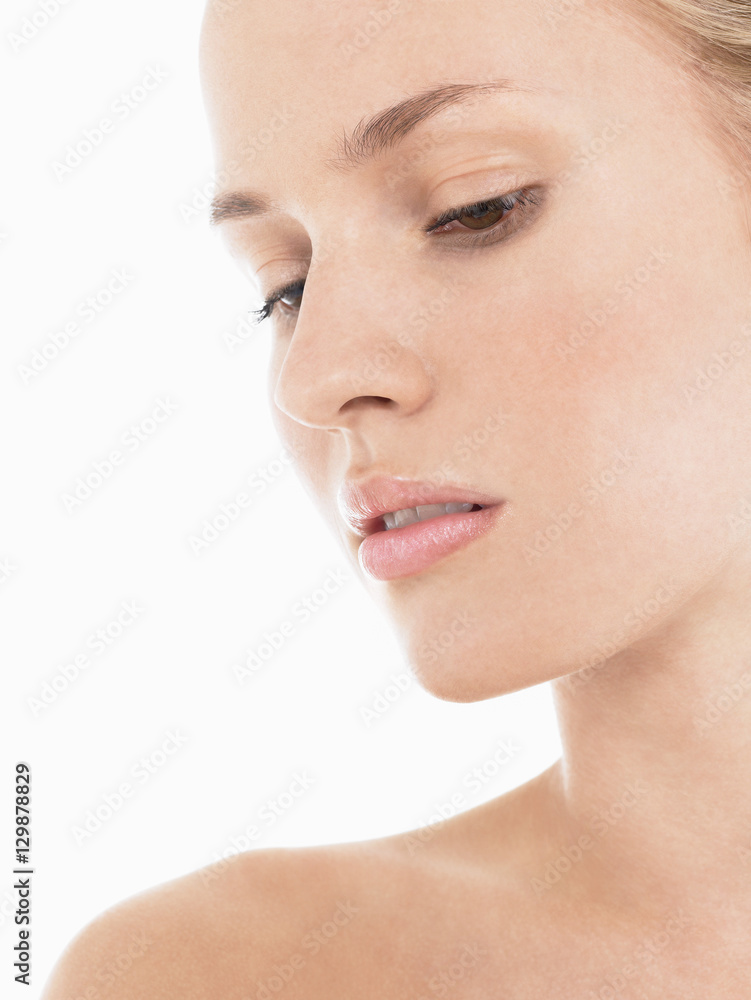 Closeup of a beautiful young woman looking down against white background Closeup of a beautiful young woman looking down against white background
