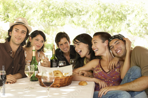 Portrait of young friends with drinks and bread basket at table enjoying party