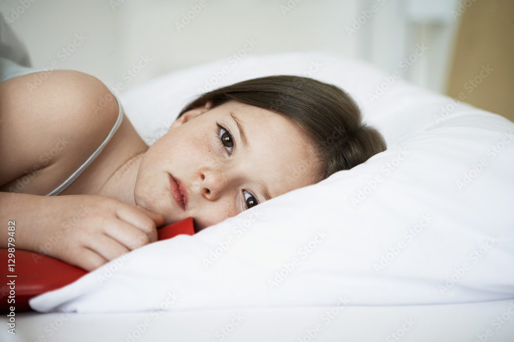 Portrait of sick little girl with hot water bottle in bed