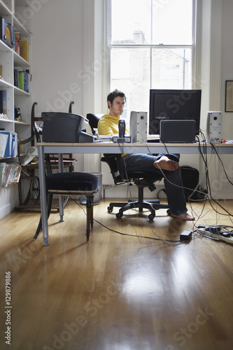 Young man working on computer in study room at home © moodboard