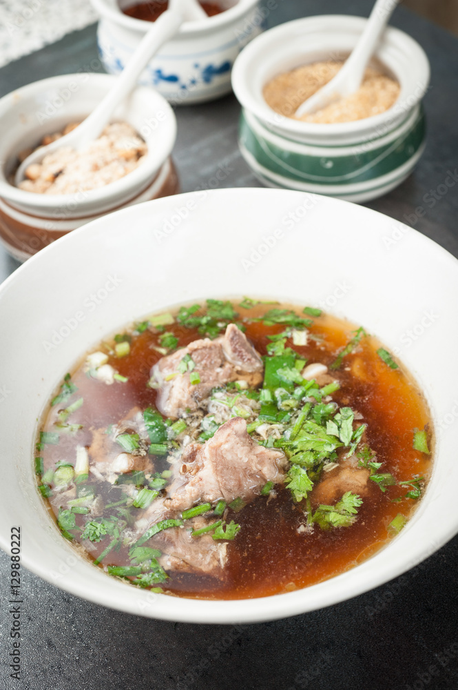 Asian style pork bone soup with seasoning on dark stone background Asian style pork bone soup with seasoning on dark stone background