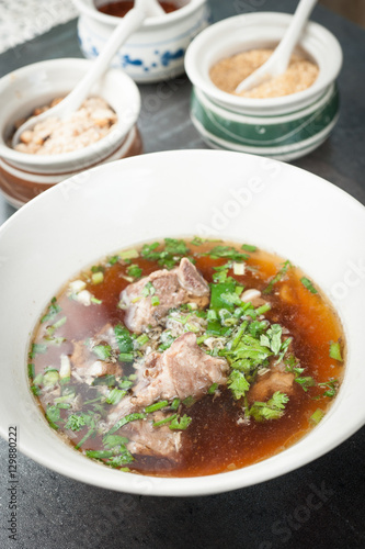 Asian style pork bone soup with seasoning on dark stone background