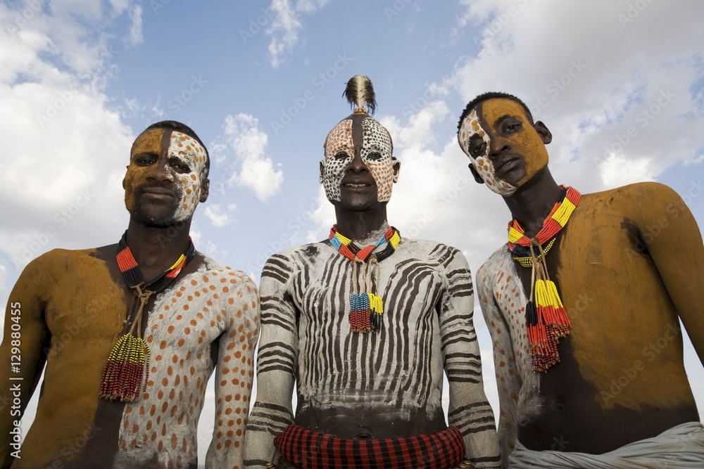 Three Karo tribesmen with face and body decoration in chalk, imitating the spotted plumage of the guinea fowl, Omo river, Lower Omo Valley, Ethiopia Three Karo tribesmen with face and body decoration in chalk, imitating the spotted plumage of the guinea fowl, Omo river, Lower Omo Valley, Ethiopia