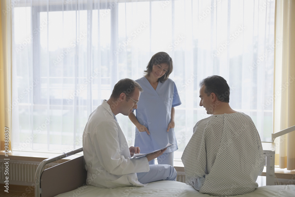 Doctor and nurse communicating with patient in hospital room Doctor and nurse communicating with patient in hospital room