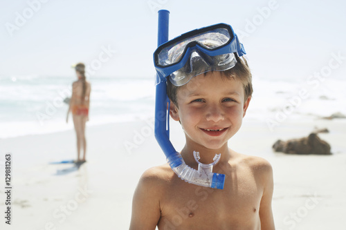 Portrait of cute little boy wearing snorkel while standing on beach © moodboard