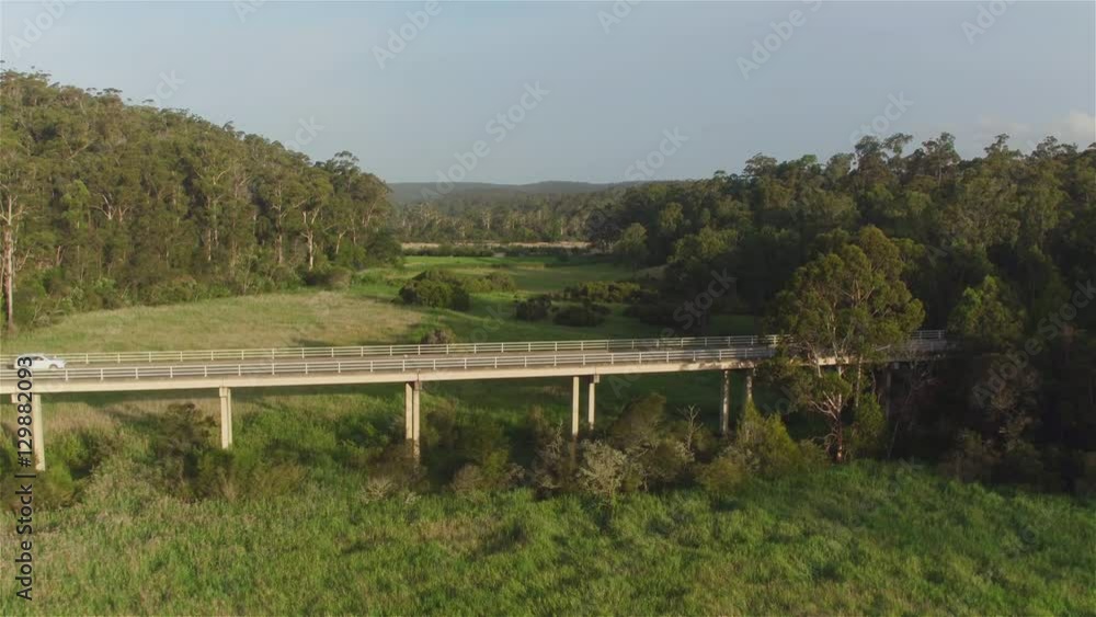 AERIAL: White car driving across the bridge over green Australian swamp AERIAL: White car driving across the bridge over green Australian swamp