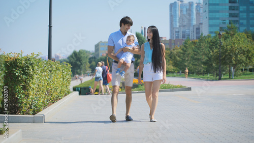 Young parents and son walking down the alley. © kustvideo