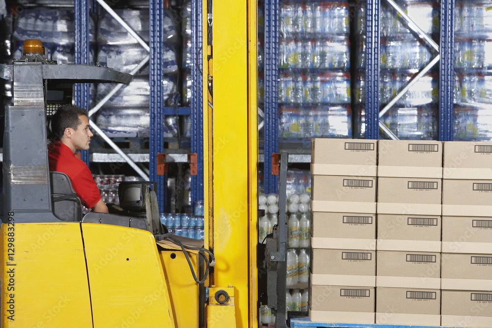 Side view of a warehouse worker operating forklift Side view of a warehouse worker operating forklift