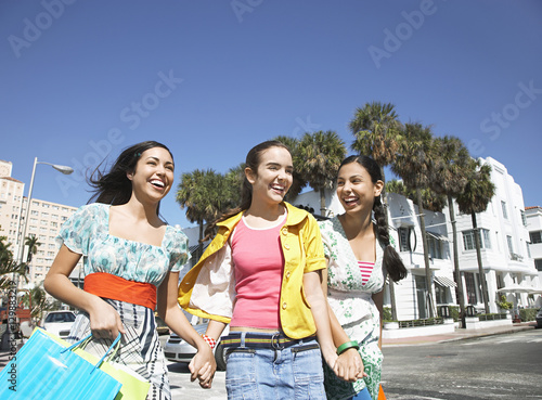 Cheerful teenage girls with shopping bags walking on street