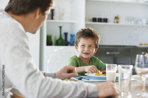 Young boy having meal with father at dining table