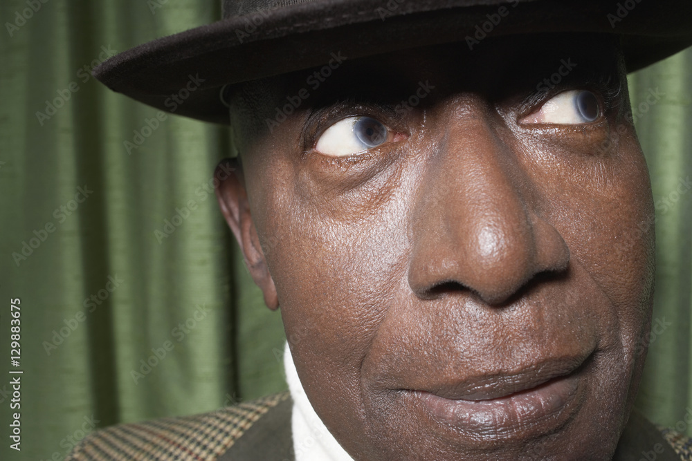 Closeup of an African American senior man wearing a hat against green curtain Closeup of an African American senior man wearing a hat against green curtain