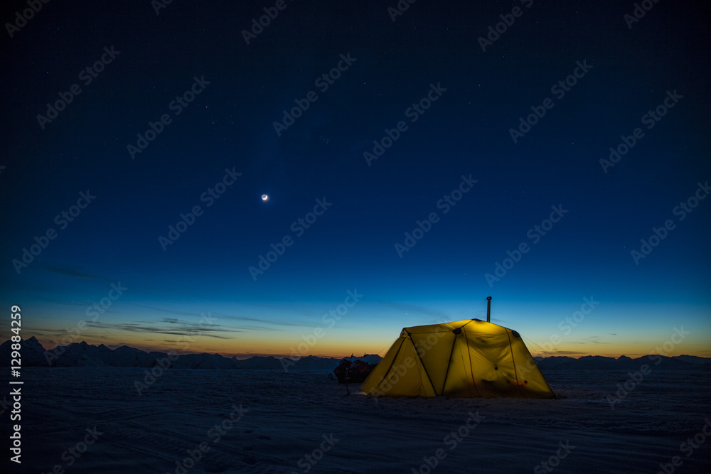 Camping in tent on the snow in the mountains at night dusk