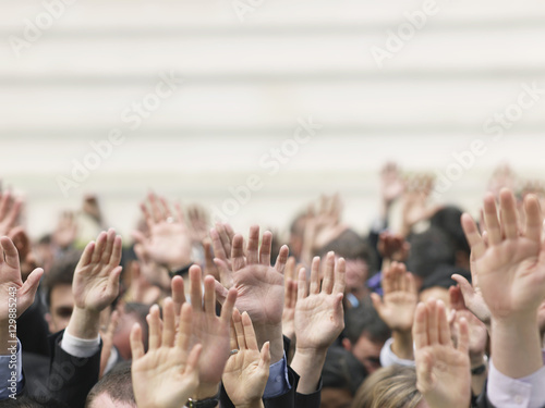 Closeup of business crowd raising hands