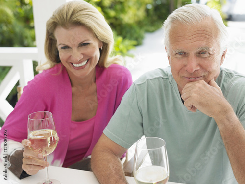 Happy middle aged couple holding wine glasses at outdoor table