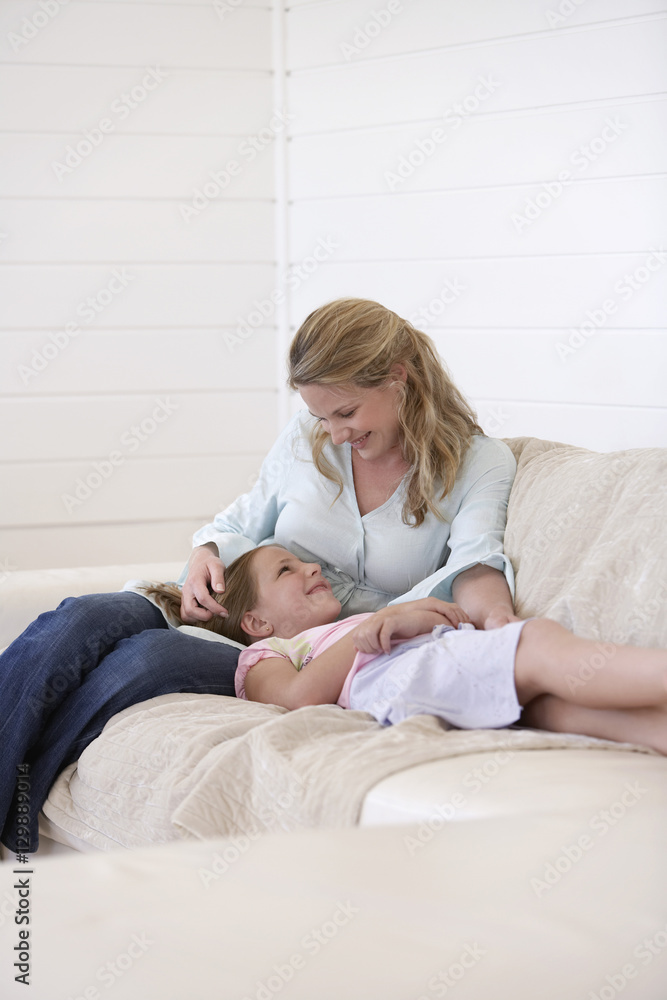 Happy mother and daughter looking at each other while relaxing on sofa Happy mother and daughter looking at each other while relaxing on sofa