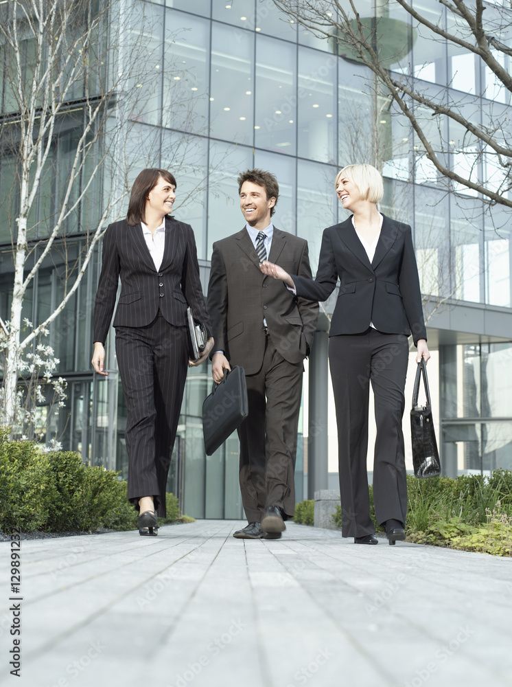 Full length of three business people walking outside office building Full length of three business people walking outside office building