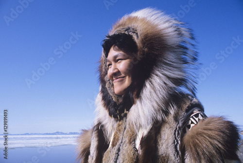Fototapeta Smiling Eskimo woman wearing traditional clothing in wind against clear blue sky