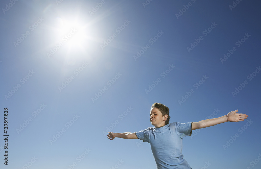 Young boy with arms outstretched in front of blue sky Young boy with arms outstretched in front of blue sky