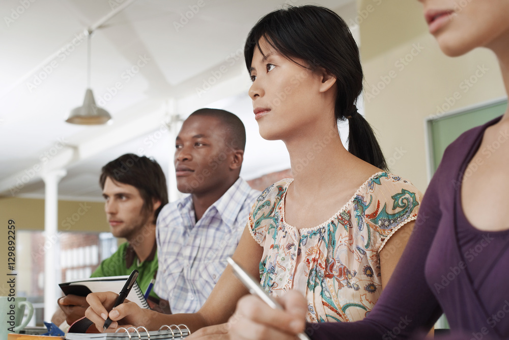 Four multiethnic people sitting and taking notes Four multiethnic people sitting and taking notes