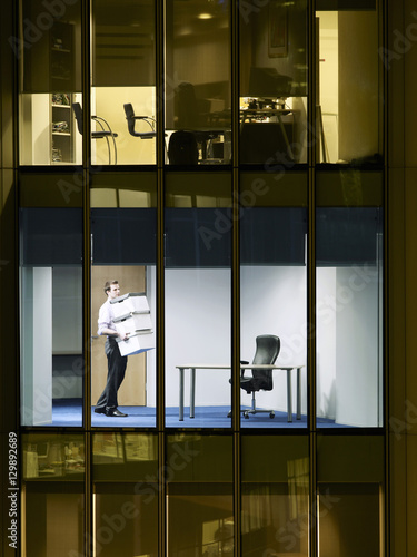 Young businessman carrying stack of boxes in office at late night