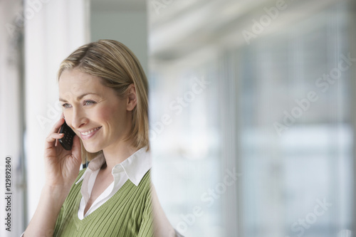 Side view of a blond businesswoman using mobile phone in office