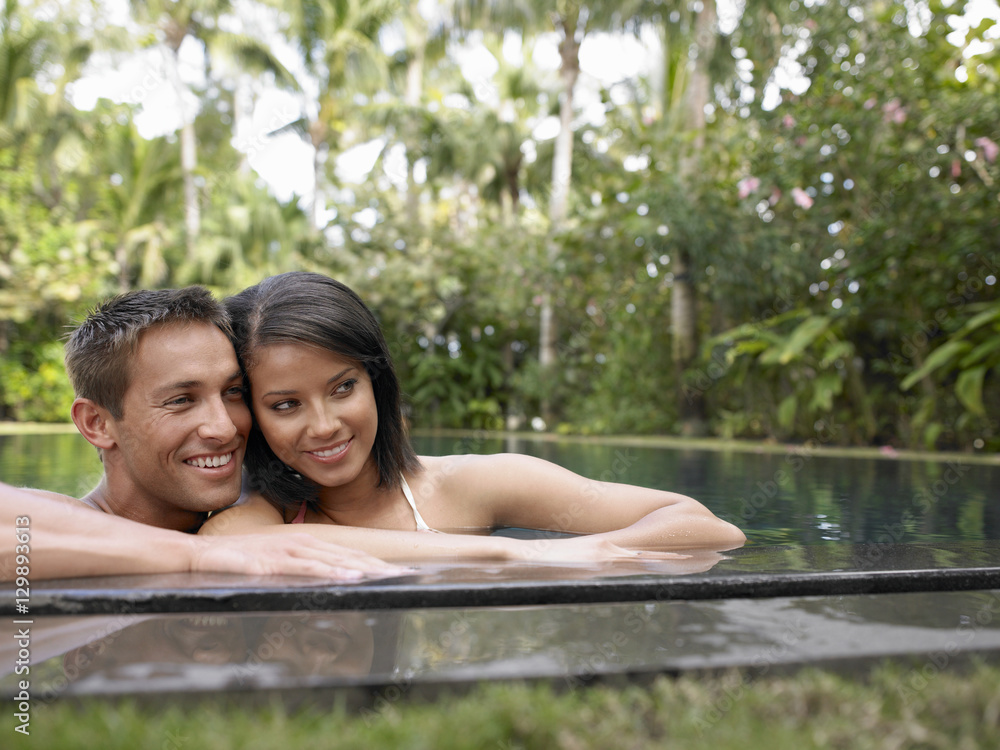 Happy young couple looking away in swimming pool