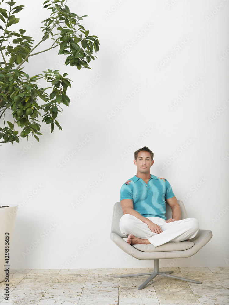 Full length portrait of a young man sitting with legs crossed in swivel chair Full length portrait of a young man sitting with legs crossed in swivel chair