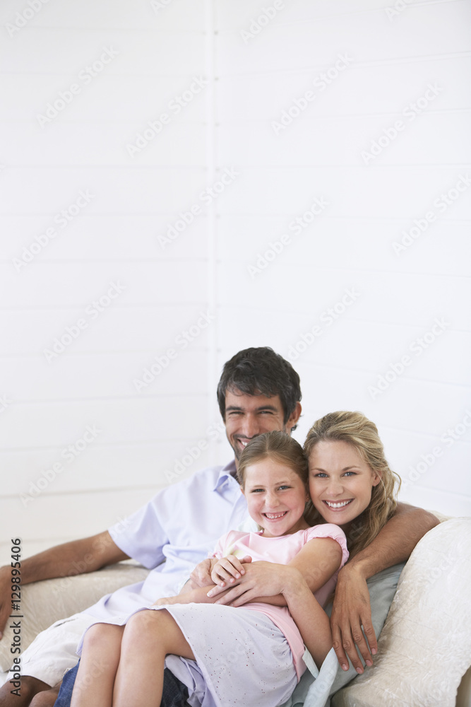 Portrait of smiling parents with daughter on sofa at home