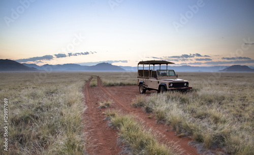 Land rover game vehicle parked by sand road at sunrise, Namib Rand game reserve, Namib Naukluft Park, Namibia