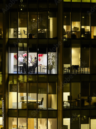 View of business people having office party through window at night